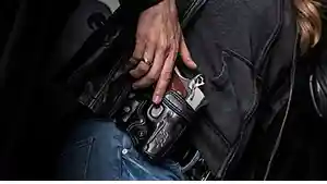 Woman with hand on a holstered gun.